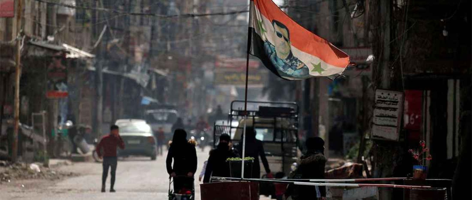 Uma bandeira nacional com a foto do presidente da Síria, Bashar al-Assad, tremula em um posto de controle em Douma, nos subúrbios de Damasco, Síria, em 10 de março de 2021 (Omar Sanadiki/Reuters).