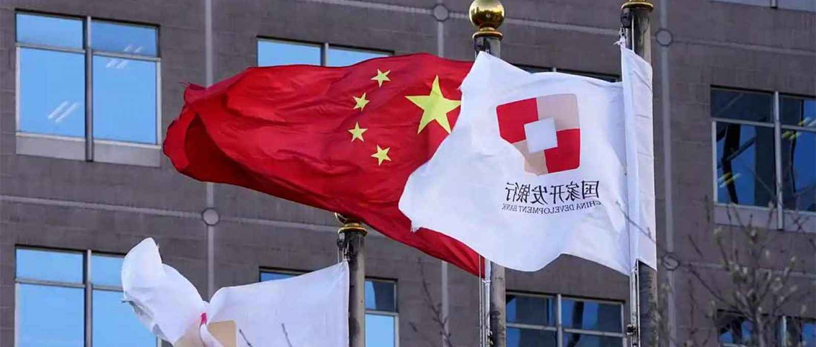 Bandeiras do Banco de Desenvolvimento da China hasteadas perto da bandeira nacional chinesa; a China tem uma variedade de instrumentos de empréstimo à sua disposição (Foto: AP).