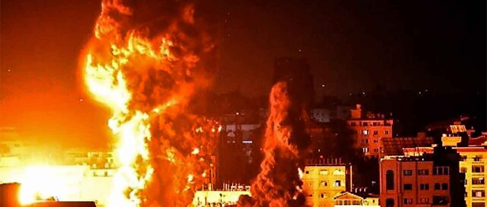 Fogo e fumaça sobem acima de edifícios na Cidade de Gaza durante ataque de aeronaves israelenses no início de 17 de maio de 2021 (Foto: Anas Baba/AFP).