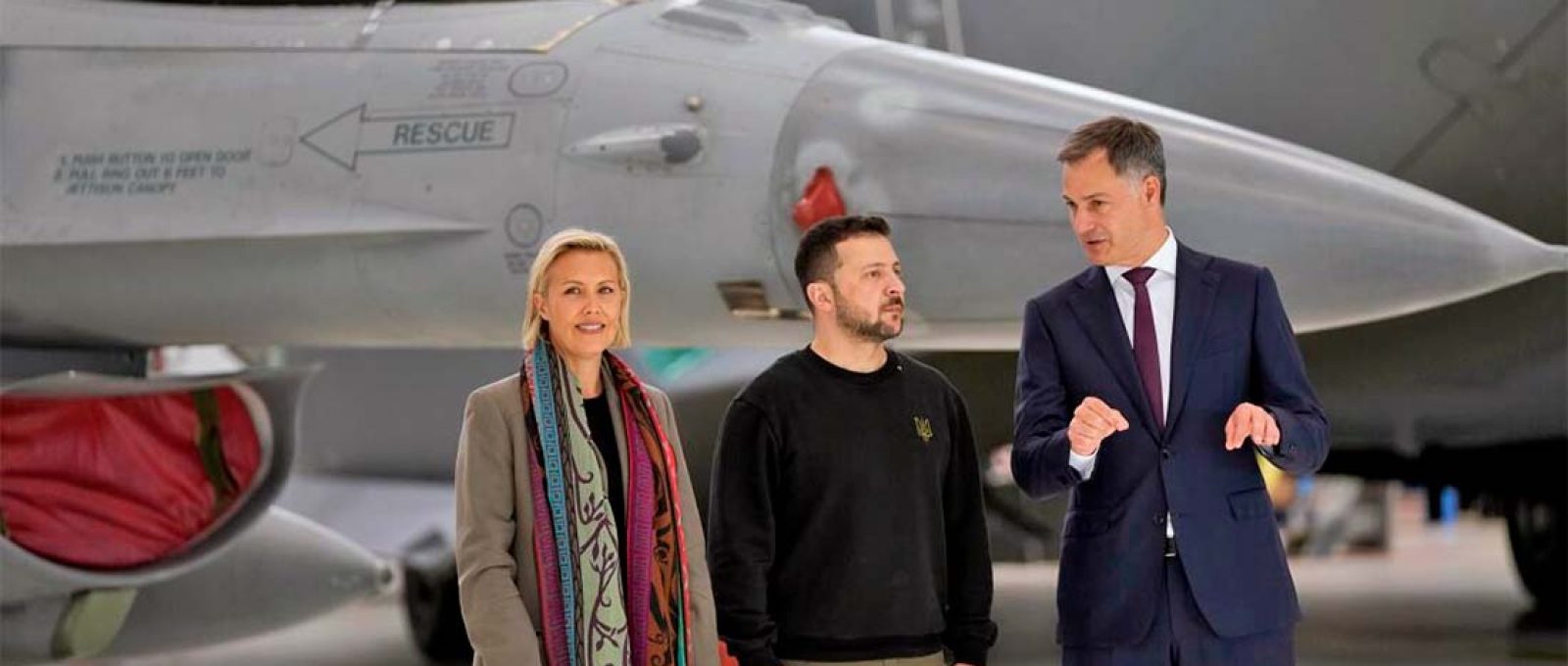 O primeiro-ministro da Bélgica, Alexander De Croo (dir.), e a ministra da Defesa da Bélgica, Ludivine Dedonder (esq.), posam com o presidente da Ucrânia, Volodymyr Zelensky, em frente a um F-16 no aeroporto militar de Melsbroek, em Bruxelas, 28 de maio (Virginia Mayo/Associated Press).