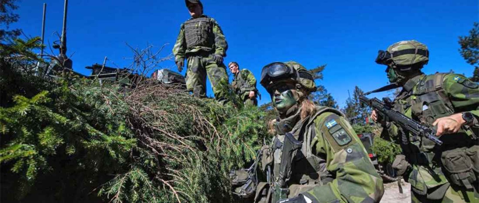 Soldados do Regimento Gotland P18 do Exército Sueco camuflam um veículo blindado durante um exercício de campo perto de Visby, na ilha sueca de Gotland, em 17 de maio (Jonathan Nackstrand/AFP via Getty Images).