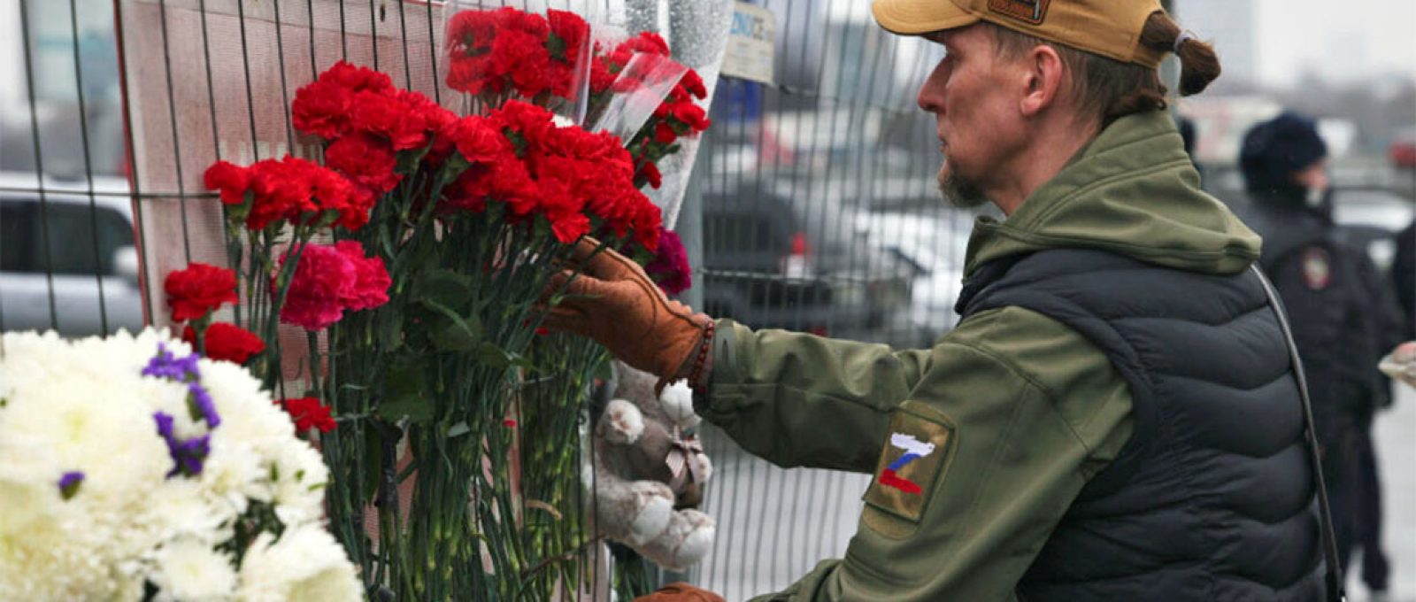 Homem coloca flores em uma cerca perto da Prefeitura de Crocus, no extremo oeste de Moscou, Rússia, no sábado, 23 de março de 2024 (Vitaly Smolnikov/AP Photo).
