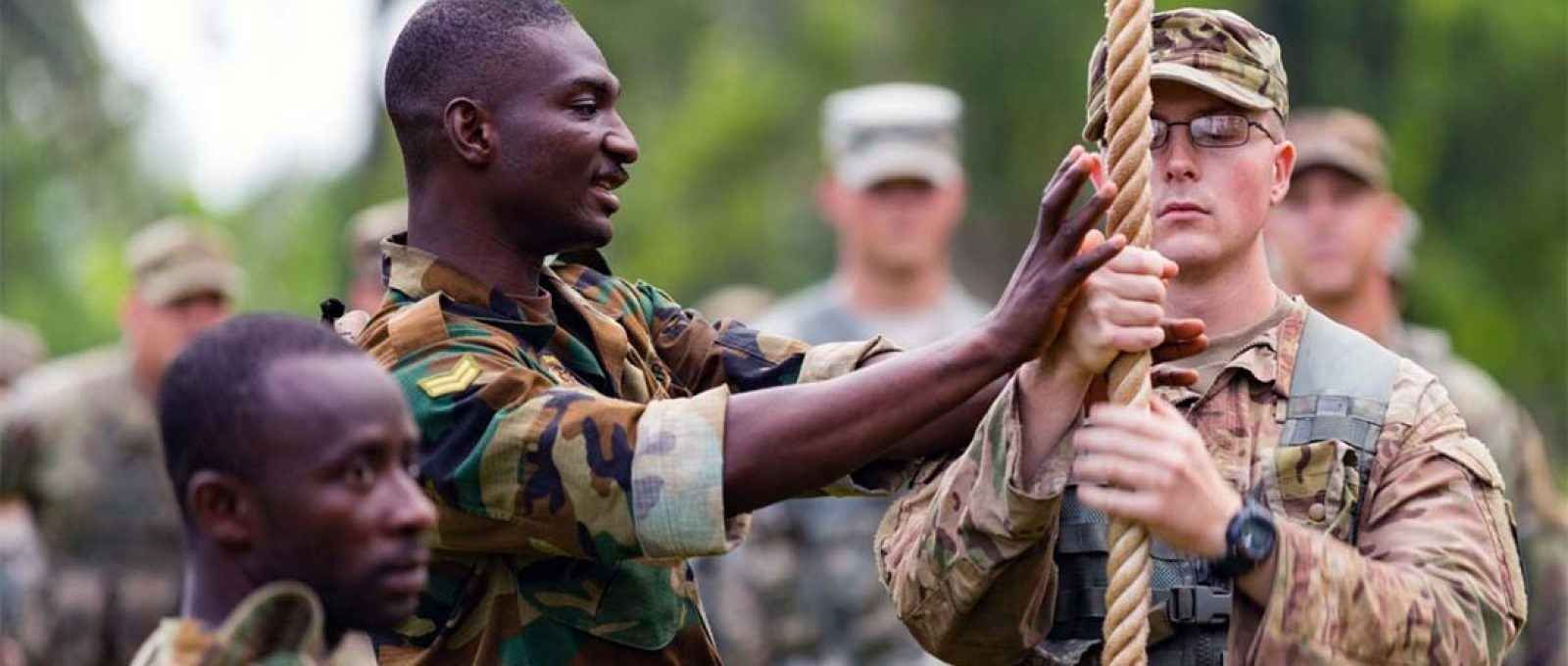 O cabo Kingsley Anyeala, do Exército de Gana, explica técnicas de escalada ao soldado Jake Burley, da 101ª Divisão Aerotransportada do Exército dos EUA na Jungle Warfare School em Akim Oda, Gana (U.S. Army).