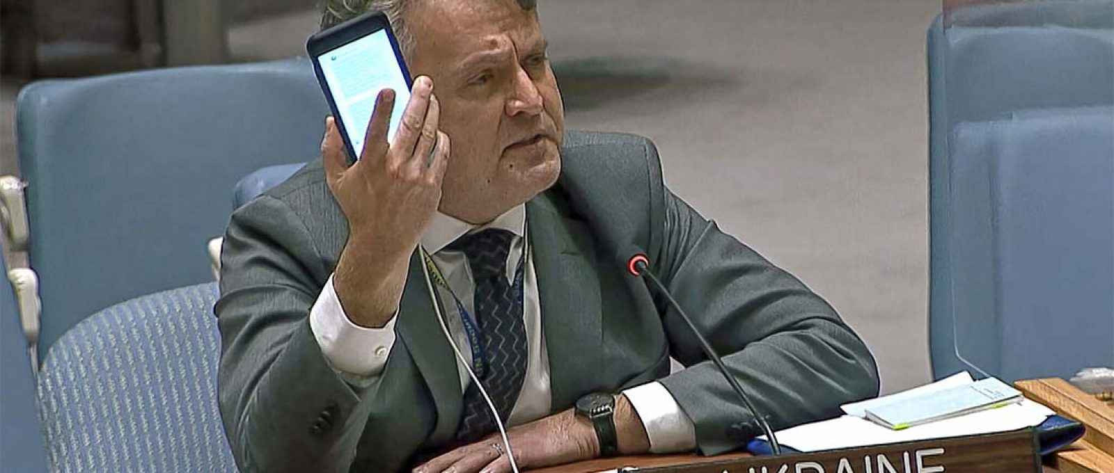 O embaixador da Ucrânia nas Nações Unidas, Sergiy Kyslytsya, segura um telefone enquanto fala em uma reunião de emergência do Conselho de Segurança na sede da ONU, 23 de fevereiro de 2022 (UNTV via AP).