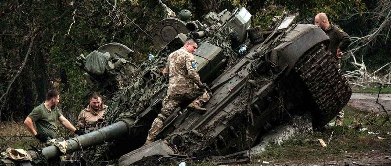 Soldados ucranianos inspecionam carro de combate russo abandonado (Yasuyoshi Chiba/AFP).