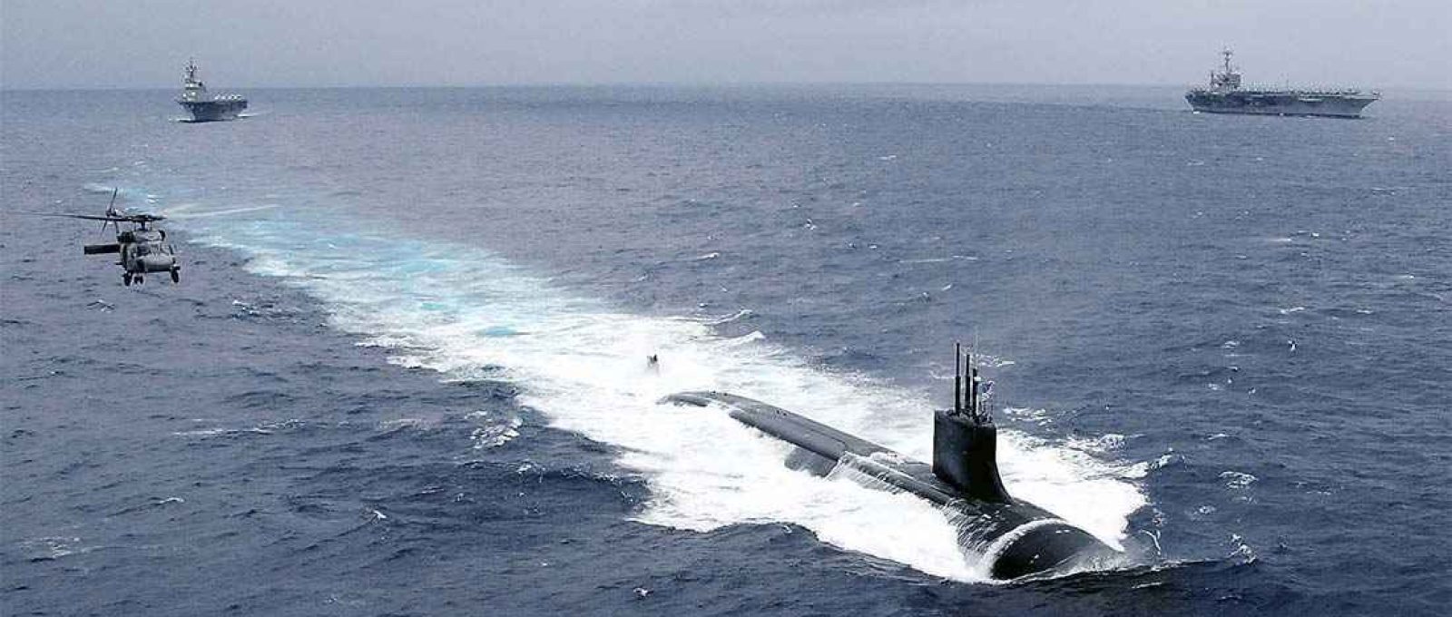 O USS Connecticut navega no Pacífico acompanhado por um helicóptero HH-60H Sea Hawk, em novembro de 2009 durante o exercício ANNUALEX 21G. Ao fundo, o porta-aviões USS George Washington e o porta-helicópteros japonês JS Hyuga (Foto: John M. Hageman/US Navy).